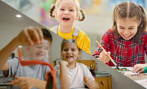 Two girls painting at a table and a boy working on a volcano project